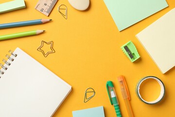 Pens and other stationery on orange background, flat lay. Space for text