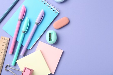 Pens and other stationery on violet background, flat lay. Space for text
