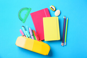 Pens and other stationery on light blue background, flat lay