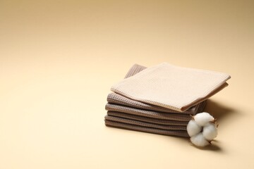Clean waffle towels and cotton flower on beige background, space for text