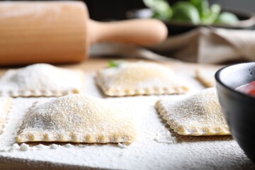 Uncooked ravioli and sauce on table, closeup