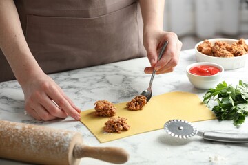 Woman making ravioli bolognese at white marble table, closeup