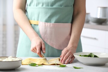 Woman cutting ravioli at light table, closeup