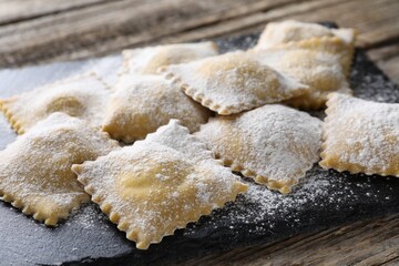 Uncooked ravioli sprinkled with flour on wooden table, closeup