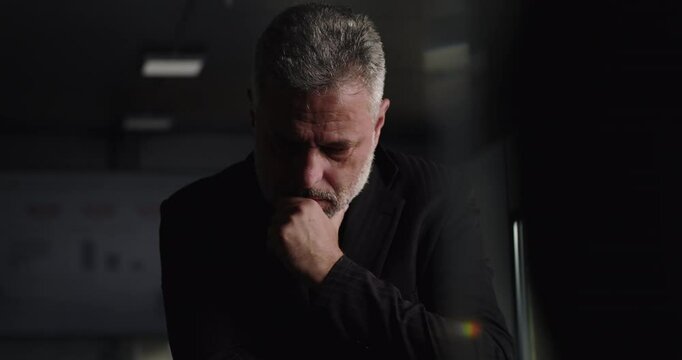 Business executive lost in thought with hand on chin during difficult company meeting in corporate boardroom with performance charts in background
