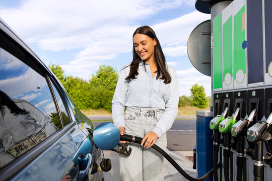 Automobile fueling offer. Smiling lady driver refilling auto with bio fuel at modern petrol station. Eco friendly and convenient car care