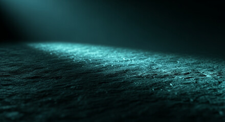 Dark rough textured surface background illuminated by a dramatic teal spotlight beam
