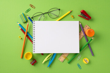 Spiral notebook placed among various school stationery including pencils, ruler, and eraser