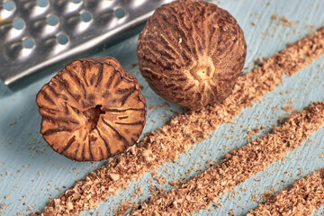 nutmegs and strands of grated mace powder on a blue painted wooden table