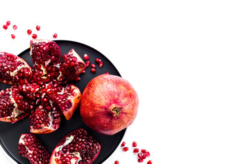 Top view of fresh ripe pomegranate and pieces on plate for eating, top view.