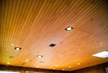 A wooden ceiling with a square light fixture on it.