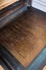 Interior of a dirty oven displaying baked on grease and unsightly stains throughout it
