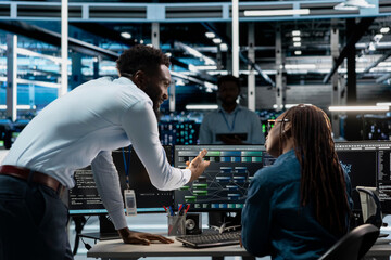 Server farm team leader overseeing work done by expert upgrading artificial intelligence systems....