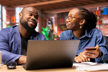 African american people at home entering card digits to renew an account subscription, managing streaming services on laptop. Couple transferring money on web, updating the credentials.