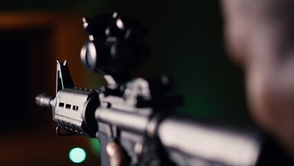 Man holds assault rifle, enjoying recreational shooting experience in firing range. Person...