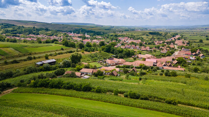 Picturesque romanian village with red roofs surrounded by cultivated fields under a cloudy sky