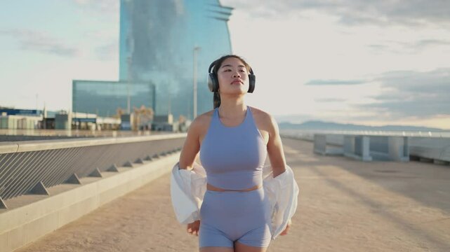 Young asian athlete removing jacket while listening music in slow motion