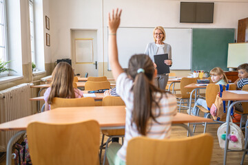 school kid raise hand to answer a question during a lesson