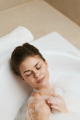 Relaxed woman enjoying a bubble bath, eyes closed and smiling, surrounded by foam and tranquility in a modern bathroom setting. Self-care and wellness concept.