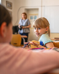 pretty school girl pupil sit in school class and talk with classmate