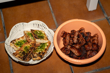 Cevapi and garlic bread resting in separate bowls after grilling