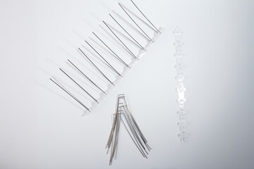 Unassembled bird deterrent spike kit with transparent plastic base and stainless steel spikes on white background. Anti-pigeon barrier components. Flat lay composition for design and print