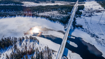 Aerial view of a bridge spanning an icy river on a cold winter day
