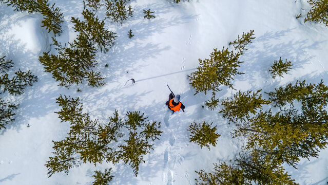 Aerial view of a young hunter stalking the snowy forest in search of game - Powered by Adobe