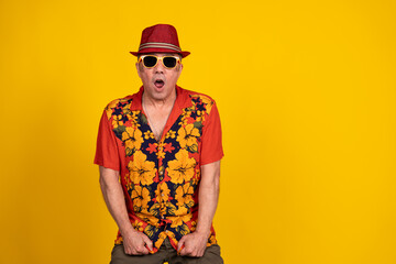 Surprised tourist wearing hawaiian shirt and sunglasses on yellow background