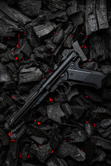 Modern pistol on glowing coal background