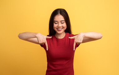 A woman with a joyful smile stands against a vibrant yellow background. She is wearing a red shirt...