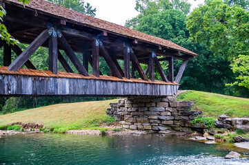 The old wooden bridge helps passengers cross the flowing river below.