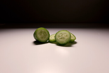 Fresh cucumber slices on clean white background under studio lighting. Minimalist healthy food...