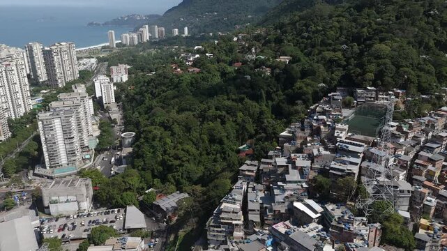 Aerial view of Rio de Janeiro, Brazil, tilt up shot flying over Favela da Rocinha towards the Pedra da Gavea Mountain on a sunny day. Rocinha is the largest favela in Brazil.	
