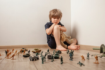 The child huddled in a corner with a teddy bear and was afraid of a toy soldiers. The child, as the...