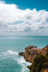 Farol da Nazare dominating the rocky coastline under a cloudy sky in Portugal