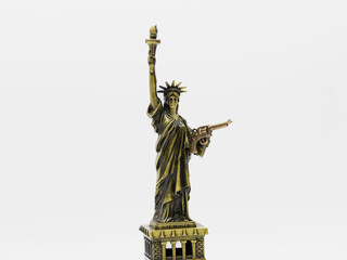 Miniatura de la estatua de la Libertad con una pistola en su mano izquierda, aislado en blanco