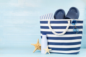 Blue beach bag with summer accessories on wooden table