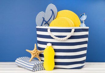 Blue beach bag with summer accessories on wooden table