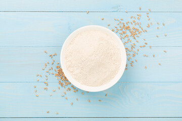Bowl with spelt flour on wooden background, top view