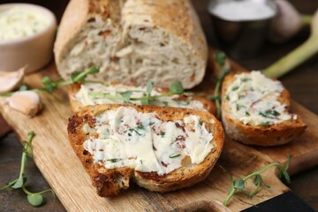 Tasty bread with garlic, herbs and oil on wooden table, closeup