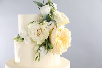 Delicious wedding cake decorated with flowers on grey background, closeup. Space for text