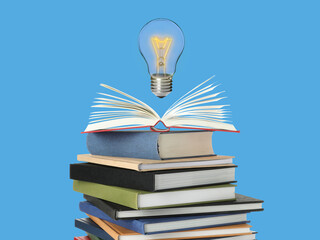 Light bulb in air over stack of books on light blue background. Idea and knowledge