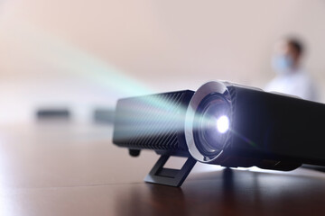 Modern video projector on table indoors, selective focus. Displaying image