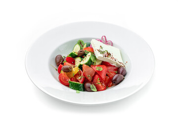 Greek salad of fresh vegetables with tomatoes, onions, bell pepper, cucumbers, olives, feta cheese in plate isolated on white background. Healthy food, vegetarian dieting, top view, close up