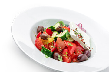 Greek salad of fresh vegetables with tomatoes, onions, bell pepper, cucumbers, olives, feta cheese in plate isolated on white background. Healthy food, vegetarian dieting, top view, close up