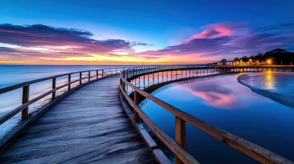 Obraz premium Scenic wooden boardwalk over water at twilight, vibrant sunset reflections and coastal pathway leading to distant shoreline