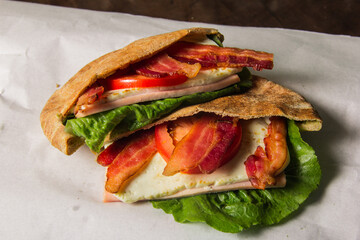 A delicious pita half stuffed with crispy bacon, melted cheese, lettuce, and tomatoes reveals a delightful combination that excites the taste buds.