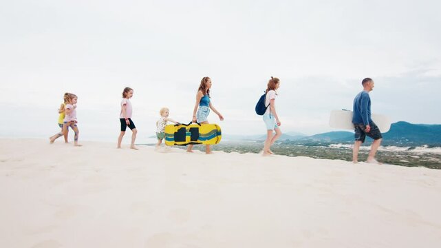 Family sandboarding. Family with kids walk on top of a sand dune with boards
