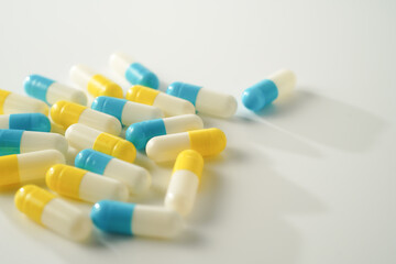 Capsules pill white blue yellow scattered on white surface, health care, medical background